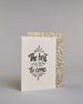 Karte in Englisch mit der Aufschrift „The best is yet to come“ in schwarzer Handlettering-Schrift, teilweise mit goldfarbenen Akzenten hervorgehoben. Über und unter dem Text sind kleine stilisierte, ebenfalls verglitzerte Feuerwerksmotive abgebildet. Dazu ein weiß-goldenes handgeschöpftes Kuvert. #3