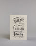Karte in Englisch mit der Aufschrift „Friends become our chosen family“ in schwarzer Handlettering-Schrift auf hellem Hintergrund. Kleine dekorative Elemente wie Linien, Zweige und Schnörkel verzieren den Text. Dazu ein grün-goldenes handgeschöpftes Kuvert. #1