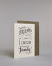 Karte in Englisch mit der Aufschrift „Friends become our chosen family“ in schwarzer Handlettering-Schrift auf hellem Hintergrund. Kleine dekorative Elemente wie Linien, Zweige und Schnörkel verzieren den Text. Dazu ein grün-goldenes handgeschöpftes Kuvert. #3