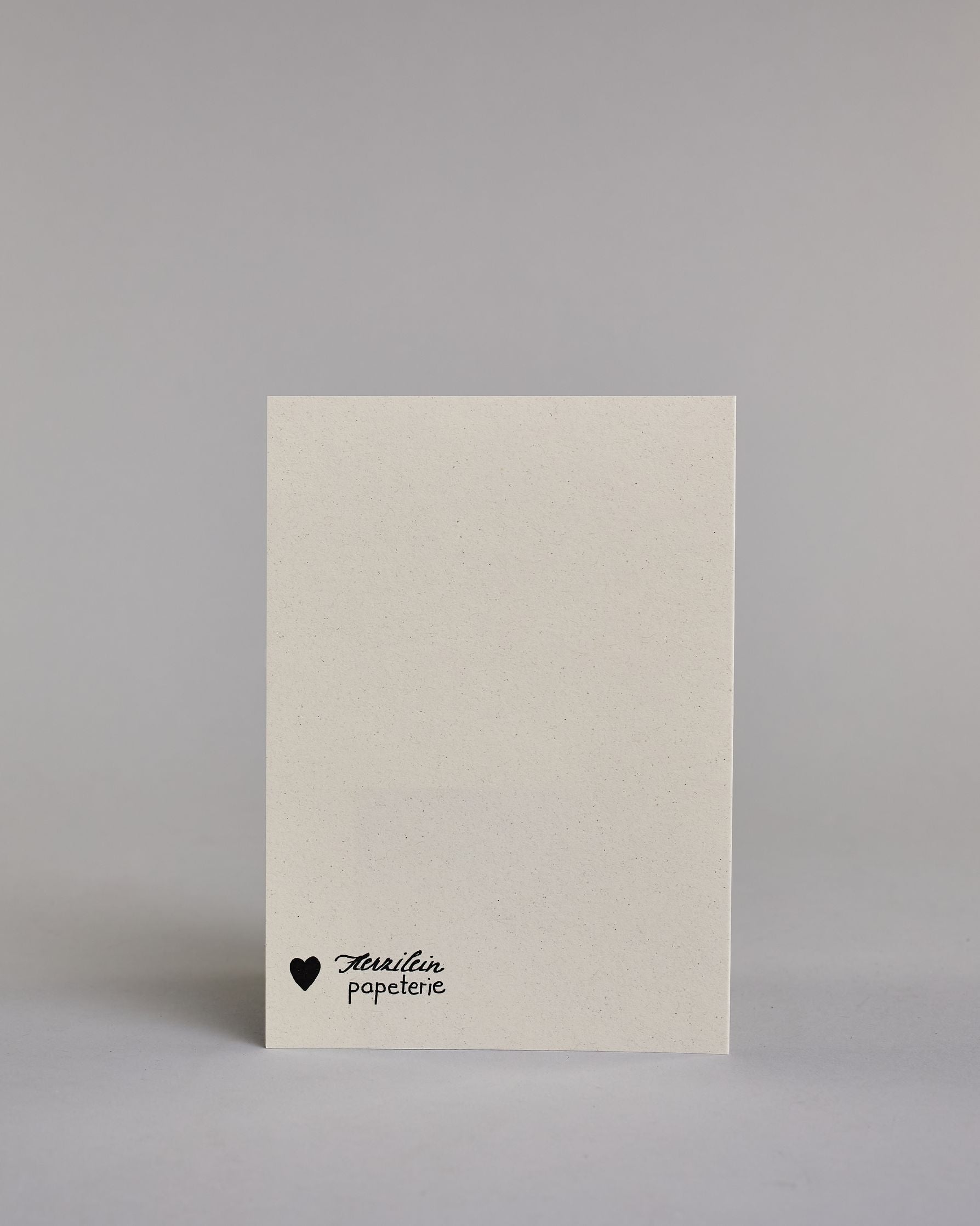 Karte mit der Aufschrift „Familie wo das Leben beginnt & die Liebe niemals endet!“ in schwarzer Handlettering-Schrift auf hellem Hintergrund. Feine Linienornamente rahmen den Text dekorativ ein. Das Design ist schlicht und elegant. Herausgehoben sind die Wörter "Familie", "Leben" und "Liebe". Dazu ein grün-goldenes handgeschöpftes Kuvert. #4