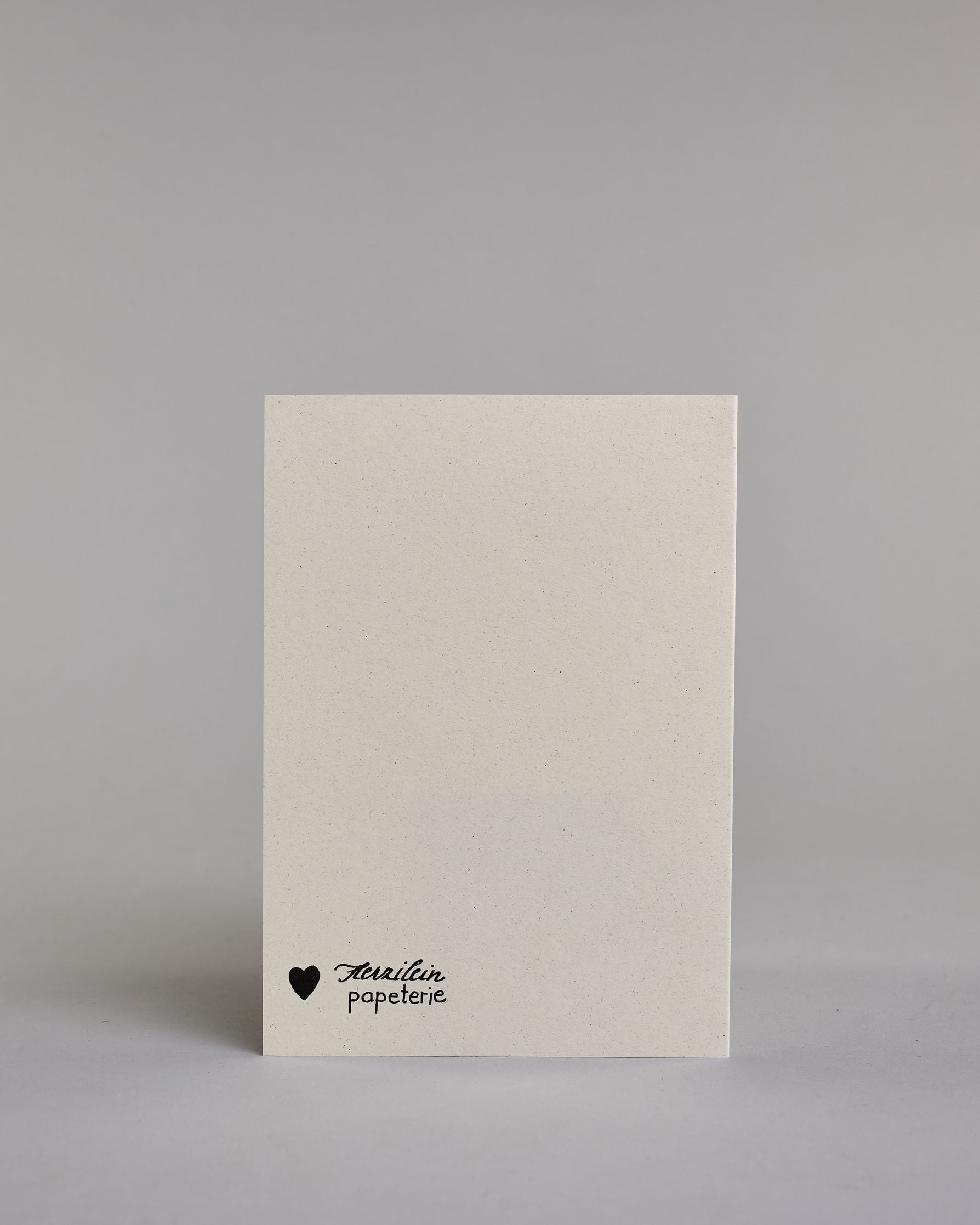 Karte mit der Aufschrift „Adventure is calling & good luck“ in schwarzer Handlettering-Schrift auf hellem Hintergrund. Über dem Wort „adventure“, welches mittig auf der Karte zu finden ist sind stilisierte Berge gezeichnet, darunter ein kleiner Weg. Zwei Pfeile rahmen das Design seitlich ein, was zu einer kreisrunden Optik führt. Dazu ein grün-goldenes handgeschöpftes Kuvert. #4