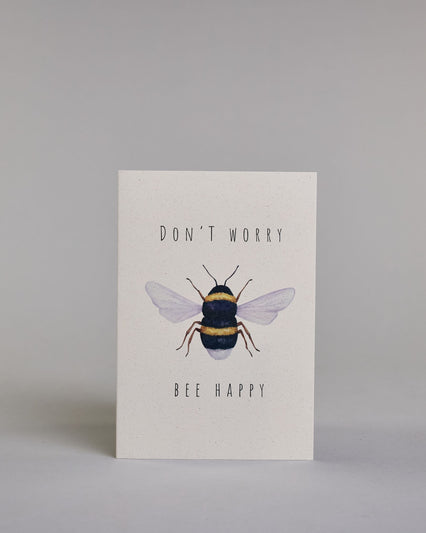 Karte auf Englisch mit der Aufschrift „Don’t worry Bee happy“ in schwarzer Schrift auf hellem Hintergrund. In der Mitte ist eine detailreich gezeichnete Biene mit gelb-schwarzem Körper und durchscheinenden Flügeln abgebildet. Dazu ein weißes handgeschöpftes Kuvert. #1