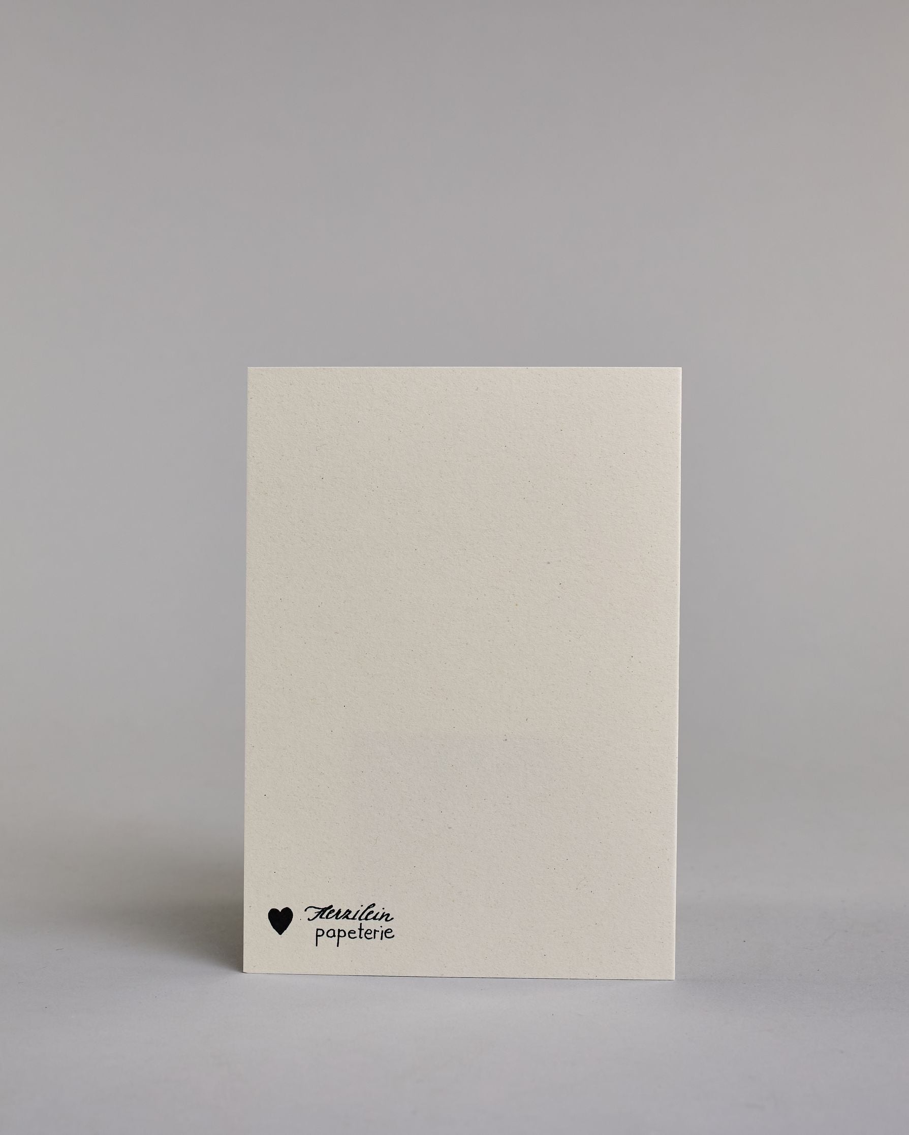 Karte auf Englisch mit der Aufschrift „Close your eyes and make a wish“ in feiner schwarzer Kalligrafieaufschrift auf hellem Hintergrund. Links unten sind zarte Pusteblumen abgebildet, deren Samen sanft quer über die Karte verwehen. Dazu ein weißes handgeschöpftes Kuvert. #4