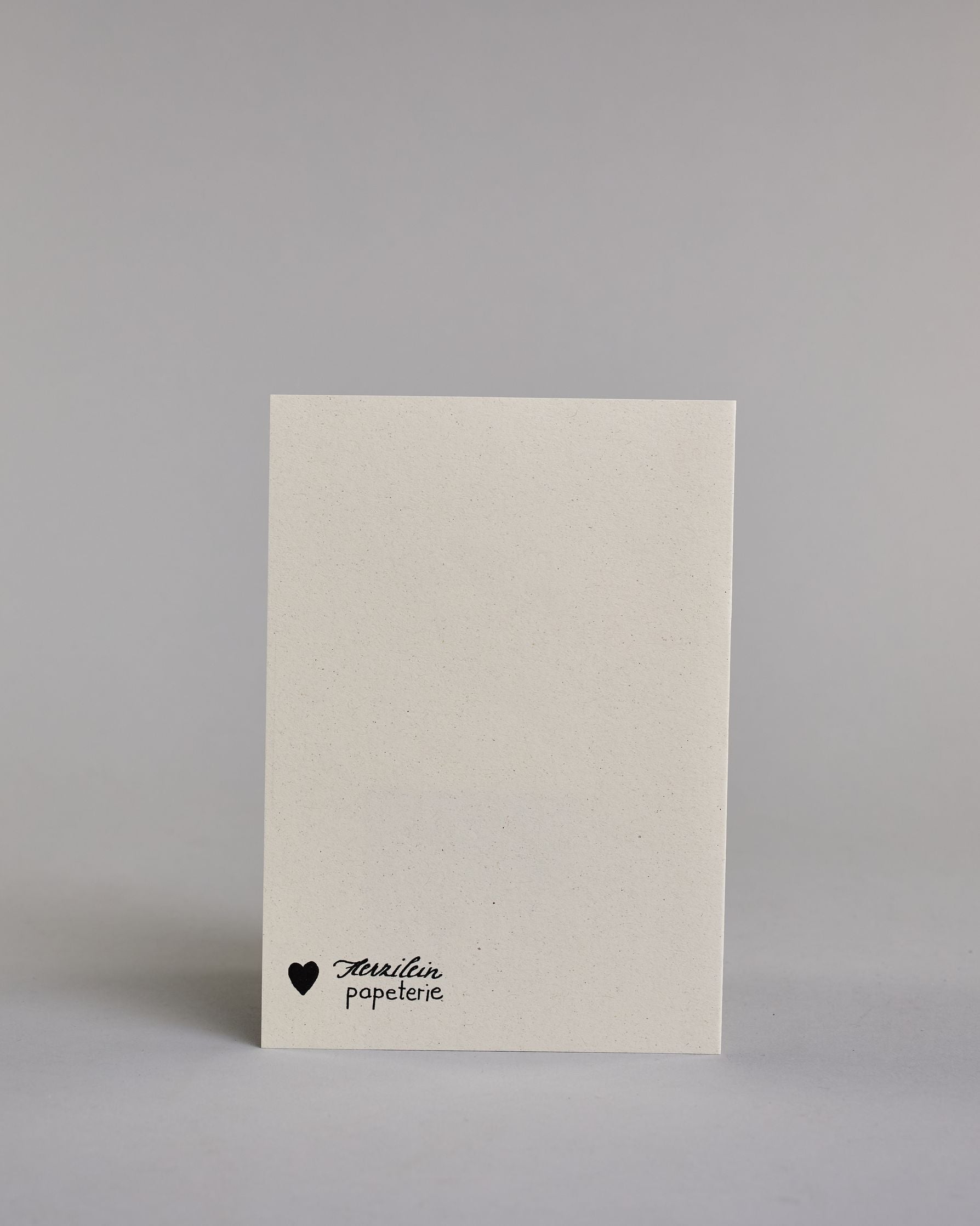 Glückwunschkarte zum Geburtstag mit schwarzer Kalligrafieaufschrift "Herzlichen Glückwunsch zum Geburtstag", darüber eine dreistückige Geburtstagstorte auf einem Tortenständer mit sechs Kerzen auf dem obersten Tortenstock. Torte, Tortenständer, als auch Kerzen sind mit Gold und Golzglitzer verziert, über den Kerzen sind in Goldglitzer Funken angedeutet. Der Text ist in drei Zeilen aufgeteilt und alles ist in einer dickeren geschwungenen Schrift gehalten. Erst "Herzlichen Glückwunsch" eher kleiner gehalten,…