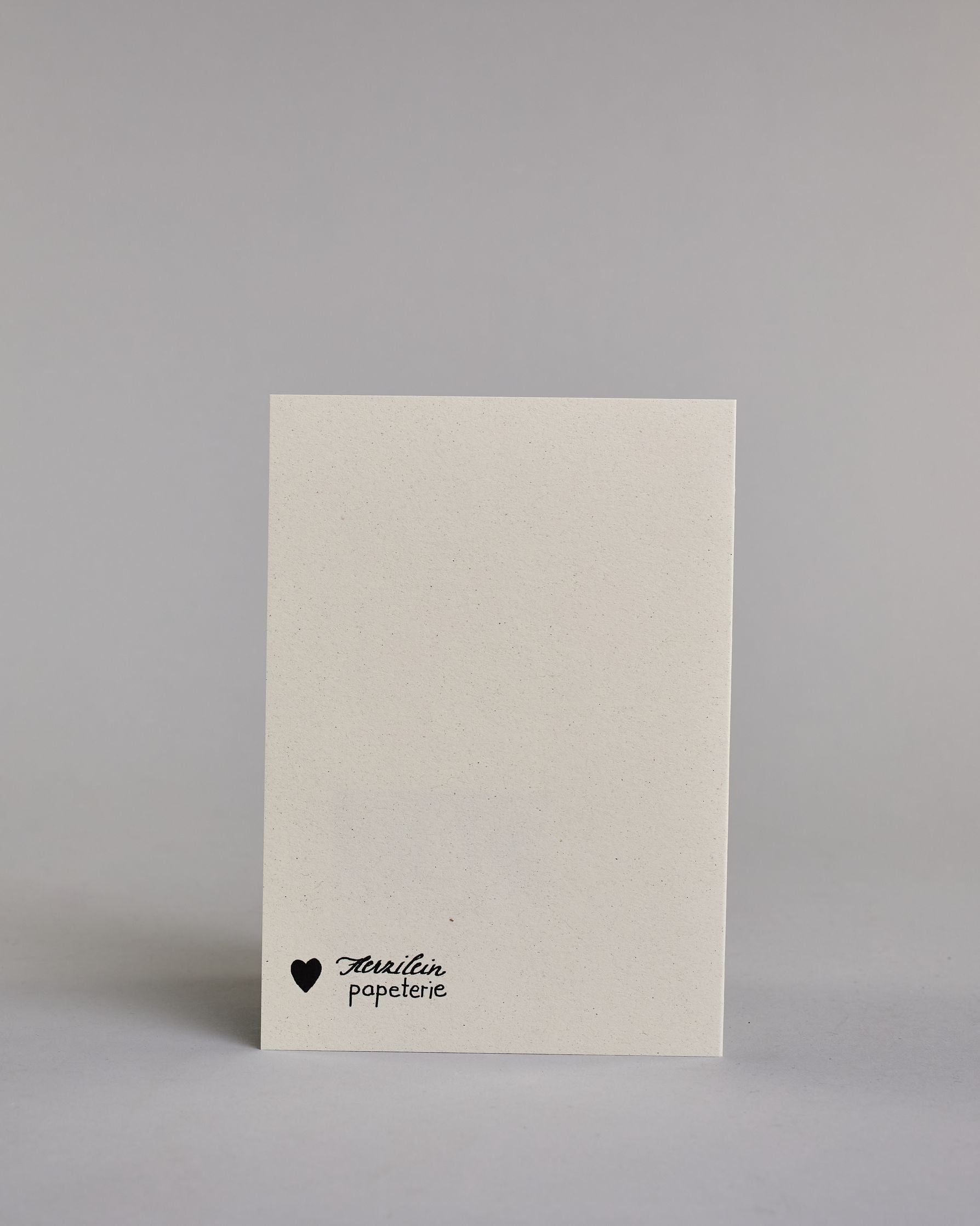 Glückwunschkarte zum Geburtstag mit schwarzer Kalligrafieaufschrift "Taa taa tusch applaus Glückwunsch und alles Gute". Die Worte sind auf fünf Zeilen aufgeteilt, welche wiefolgt aufgeteilt sind: "TAA TAA", darunter "TUSCH", beide Zeilen sind in Blockbuchstaben und die Buchstaben sind mit Gold gefüllt, rundherum sind dekorative Strahlen, darunter in geschwungener Schreibschrift "applaus", darunter "GLÜCKWUNSCH" in dünner, gerader Kalligrafieschrift, darunter "und alles Gute" in kleiner, dünner Schreibschri…