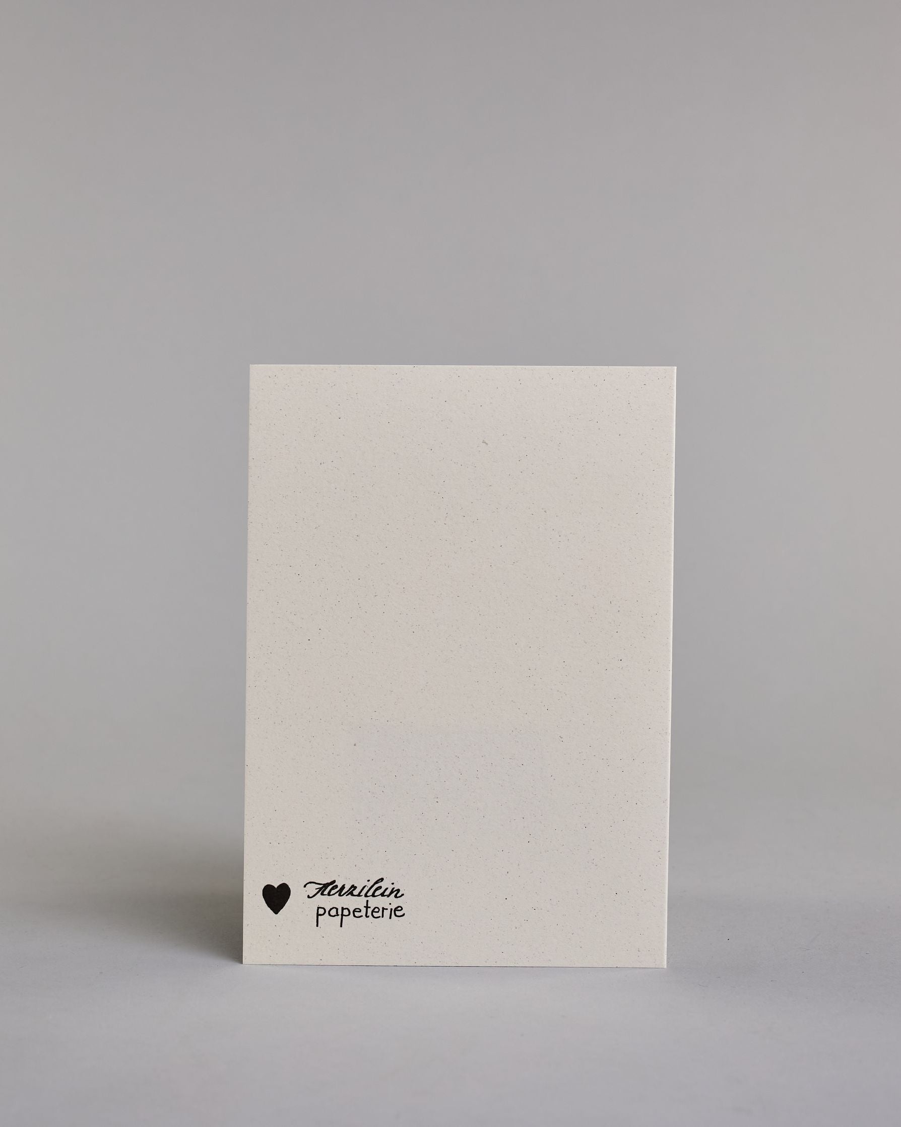Glückwunschkarte auf Englisch zum Geburtstag mit der Aufschrift "Happy birthday blah blah blah ...gin!" in schwarzer, goldakzentuierter Schrift auf hellem Hintergrund. Die Zeilen sind wiefolgt aufgeteilt: "HAPPY", darunter "birthday" beides in eher dickerer Schrift, darunter "BLAH BLAH", darunter "BLAH..." beide Zeilen in dünner gerader Kalligrafieschrift,  darunter "...Gin!" wie in geschwungener dickeren Schrift. Dazu ein grün-goldenes handgeschöpftes Kuvert. #4