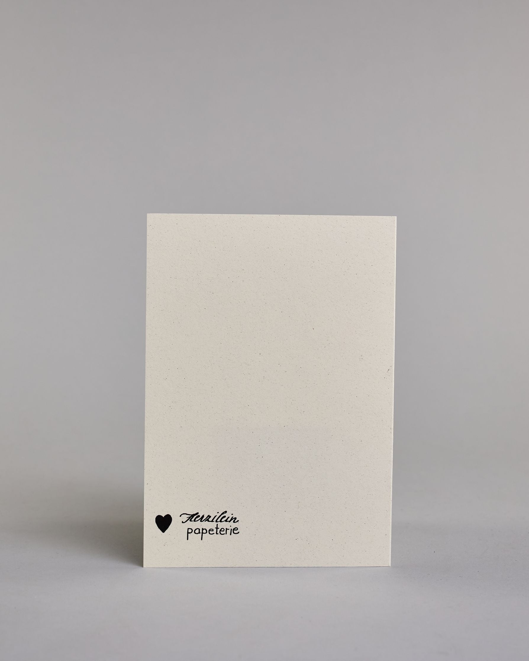 Glückwunschkarte zum Geburtstag mit schwarzer Kalligrafieaufschrift "Lasst uns feiern". Der Text ist auf drei Zeilen aufgeteilt, welche jeweils immer ein Wort beinhalten. Die Schrift ist eine große geschwungene Schreibschrift mit Goldakzenten auf hellem Hintergrund. Dazu ein grün-goldenes handgeschöpftes Kuvert. #4