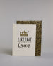 Glückwunschkarte auf Englisch zum Geburtstag mit schwarzer Kalligrafieaufschrift "Birthday Queen", mit einer prunkvollen goldenen und goldglitzernden Krone. Der Text ist übereinander geschrieben mit einer horizontalen goldverzierten Linie dazwischen. Das "Birthday" ist in Blockbuchstaben und das "Queen" in geschwungener Schreibschrift auf hellem Hintergrund. Dazu ein grün-goldenes handgeschöpftes Kuvert. #2