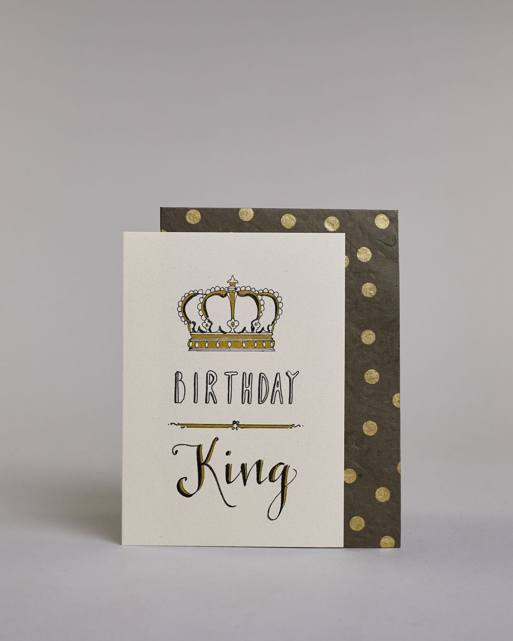 Glückwunschkarte auf Englisch zum Geburtstag mit schwarzer Kalligrafieaufschrift "Birthday King", mit einer prunkvollen goldenen und goldglitzernden Krone. Der Text ist übereinander geschrieben mit einer horizontalen goldverzierten Linie dazwischen. Das "Birthday" ist in Blockbuchstaben und das "King" in geschwungener Schreibschrift auf hellem Hintergrund. Dazu ein grün-goldenes handgeschöpftes Kuvert. #2
