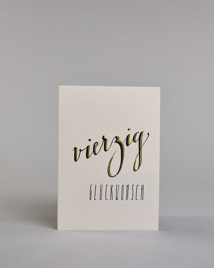 Glückwunschkarte zum Geburtstag mit schwarzer Kalligrafieaufschrift "vierzig Glückwunsch" auf hellem Hintergrund. Die ausgeschriebene Zahl ist leicht aufsteigend in geschwungener, goldverzierter Schreibschrift gestaltet und das Wort "GLÜCKWUNSCH" darunter leicht nach rechts versetzte ist in dünner, gerader Kalligrafieschrift geschrieben. Dazu ein gold-weißes handgeschöpftes Kuvert. #1