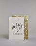 Glückwunschkarte zum Geburtstag mit schwarzer Kalligrafieaufschrift "siebzig Glückwunsch" auf hellem Hintergrund. Die ausgeschriebene Zahl ist leicht aufsteigend in geschwungener, goldverzierter Schreibschrift gestaltet und das Wort "GLÜCKWUNSCH" darunter leicht nach rechts versetzte ist in dünner, gerader Kalligrafieschrift geschrieben. Dazu ein gold-weißes handgeschöpftes Kuvert. #2