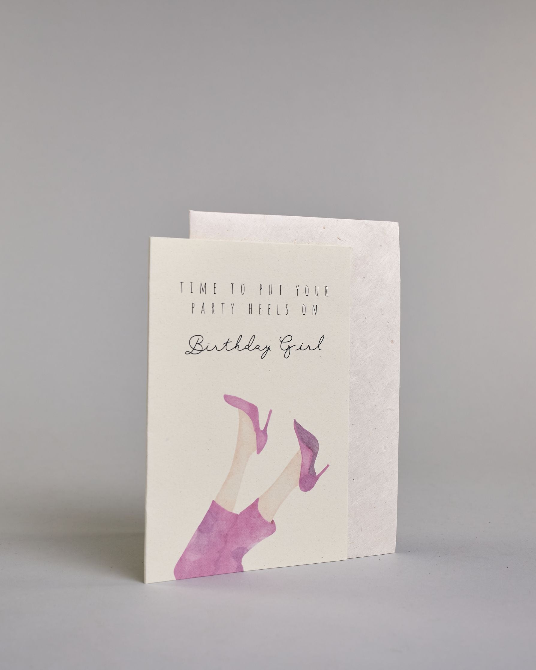 Glückwunschkarte auf Englisch zum Geburtstag mit schwarzer Kalligrafieaufschrift "time to put your party heels on Birthday girl", mit genzeichneten Damenbeinen die mit einer pinken Hose bedeckt sind und pinke Stöckelschuhe tragen auf hellem Hintergrund. Oben steht in drei Zeilen "TIME TO PUT YOUR", darunter "PARTY HEELS ON" beides in dünner gerader Kalligrafieschrift, darunter "Birthdaygirl" in geschwungener dünner Schreibschrift, darunter die Damenbeine. Dazu ein weißes handgeschöpftes Kuvert. #3