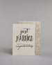 Glückwunschkarte zur Hochzeit in Englisch mit der Kalligrafieaufschrift "just MARRIED congratulations" auf hellem Hintergrund. Oben in schwungvoller schwarzer Schrift steht das Wort „just“. Darunter in größerer, dekorativer Schrift mit goldfarbenen Akzenten das Wort „MARRIED“. Der Punkt vom „I“ ist ein kleines Herz. Am unteren Rand der Karte steht in eleganter, geschwungener schwarzer Schrift „congratulations“. Dazu ein gold-weißes handgeschöpftes Kuvert. #2