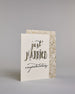 Glückwunschkarte zur Hochzeit in Englisch mit der Kalligrafieaufschrift "just MARRIED congratulations" auf hellem Hintergrund. Oben in schwungvoller schwarzer Schrift steht das Wort „just“. Darunter in größerer, dekorativer Schrift mit goldfarbenen Akzenten das Wort „MARRIED“. Der Punkt vom „I“ ist ein kleines Herz. Am unteren Rand der Karte steht in eleganter, geschwungener schwarzer Schrift „congratulations“. Dazu ein gold-weißes handgeschöpftes Kuvert. #3