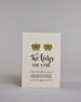 Glückwunschkarte auf Englisch zur Hochzeit für zwei Männer mit der Kalligrafieaufschrift "Two Kings make a pair congratulations" auf hellem Hintergrund. Sie zeigt oben zwei Kronen welche mit Gold verziert sind. Darunter steht in großer, geschwungener schwarzer Schrift mit goldenen Details „Two kings“, darunter mit dünner Kalligraphieschrift "MAKE A PAIR". Unterhalb davon befindet sich in ebenfalls gerader schwarzer Schrift "CONGRATULATIONS" welches sowohl ober- als auch unterhalb prunkvolle horizotale Lini…