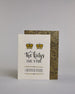 Glückwunschkarte auf Englisch zur Hochzeit für zwei Männer mit der Kalligrafieaufschrift "Two Kings make a pair congratulations" auf hellem Hintergrund. Sie zeigt oben zwei Kronen welche mit Gold verziert sind. Darunter steht in großer, geschwungener schwarzer Schrift mit goldenen Details „Two kings“, darunter mit dünner Kalligraphieschrift "MAKE A PAIR". Unterhalb davon befindet sich in ebenfalls gerader schwarzer Schrift "CONGRATULATIONS" welches sowohl ober- als auch unterhalb prunkvolle horizotale Lini…