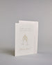 Glückwunschkarte zur Hochzeit mit hellbrauner Kalligrafieaufschrift "Hand in Hand ein Leben lang cheers to forever!". Die Karte ist wiefolgt gegliedert: "HAND IN HAND", darunter "EIN LEBEN LANG", beide Zeilen sind in einer dünnen aufrechten Kalligrafieschrift gestaltet. Darunter stoßen zwei gezeichnete Champagnergläser an, um dessen Gläserhälsen jeweils eine weiße Schleife gebunden ist. Der Champagner schwapt durch den Schwung etwas über den Glasrand und ist mit Golddeteils verfeinert. Darunter ist in gesc…