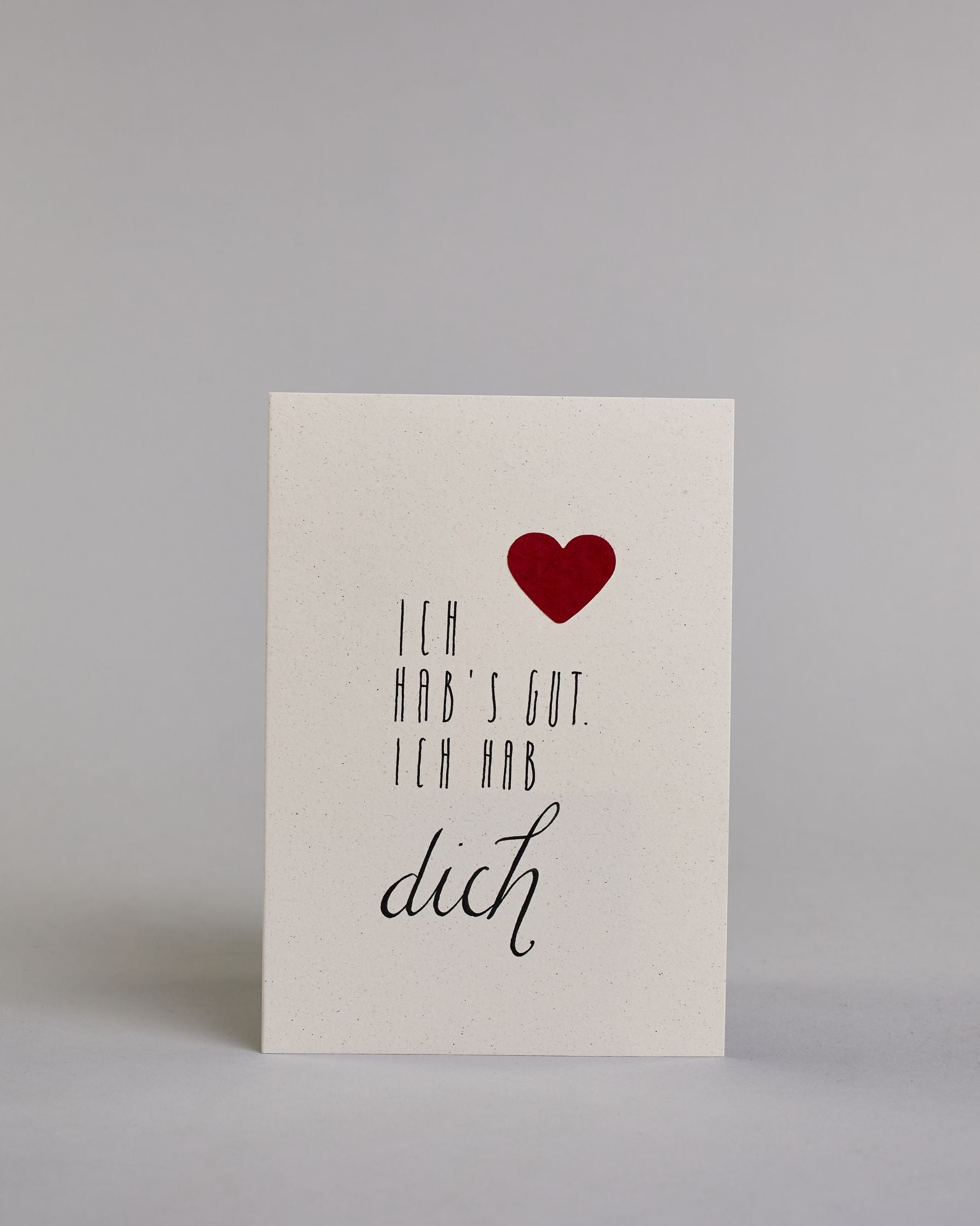 Klappkarte für Liebende mit schwarzer Kalligrafieaufschrift "Ich hab's gut. Ich hab dich" mit einem rotem aufgeklebtem Herz auf hellem Hintergrund. Die Schrift ist auf 4 Zeilen aufgeteilt. "ICH", darunter "HAB'S GUT.", darunter "ICH HAB" alles in einer dünnen geraden Kalligrafieschrift, darunter "dich" in einer geschwungenen Schreibschrift. Die Schrift ist eher linksbündig, das Herz klebt auf Höhe der ersten Zeile, mit dem "ICH" rechts auf der Karte.  Dazu ein rot-weißes handgeschöpftes Kuvert. #1
