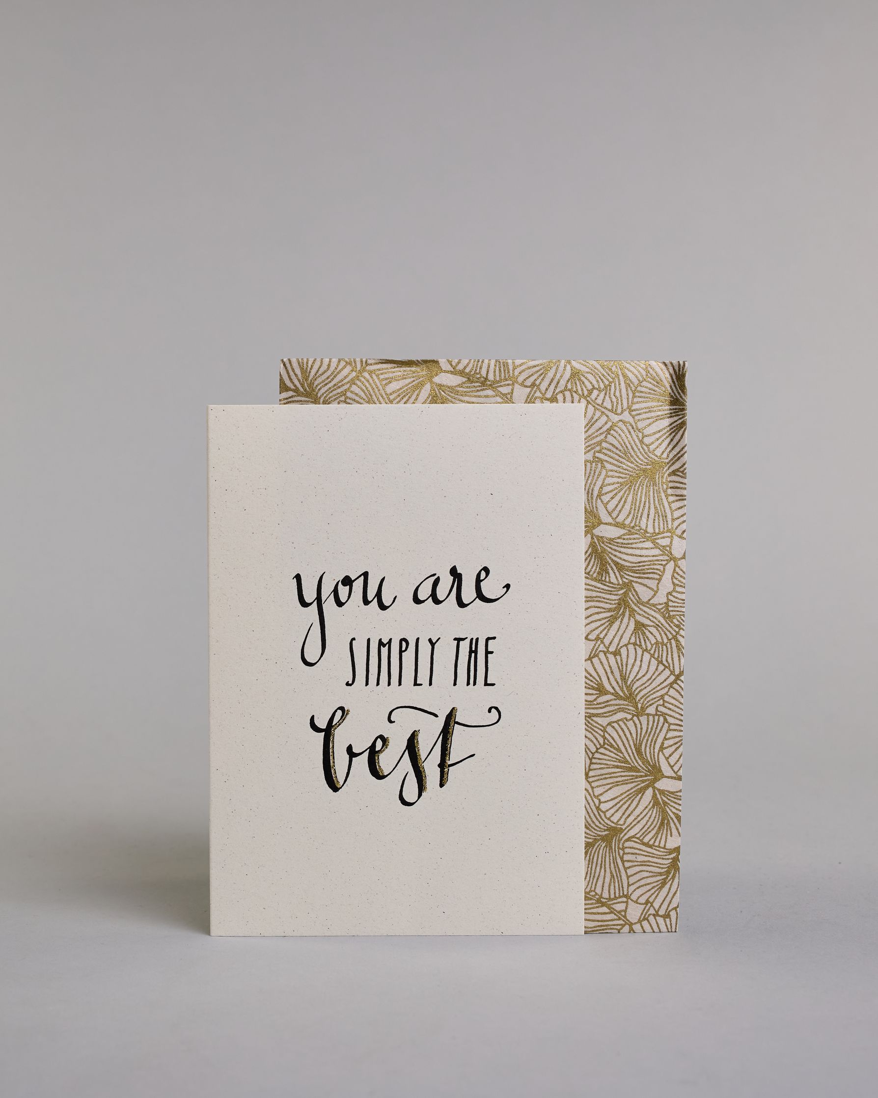 Klappkarte für Liebende auf Englisch mit schwarzer Kalligrafieaufschrift "You are simply the best" auf hellem Hintergrund. Der Text ist in folgende drei Zeilen aufgeteilt: "you are" in geschwungener Schreibschrift, darunter "SIMPLY THE" in gerader dünner Kalligrafieschrift, darunter "best" in der gleichen geschwungenen Schreibschrift wie in der ersten Zeile. Dazu ein grün-goldenes handgeschöpftes Kuvert. #2