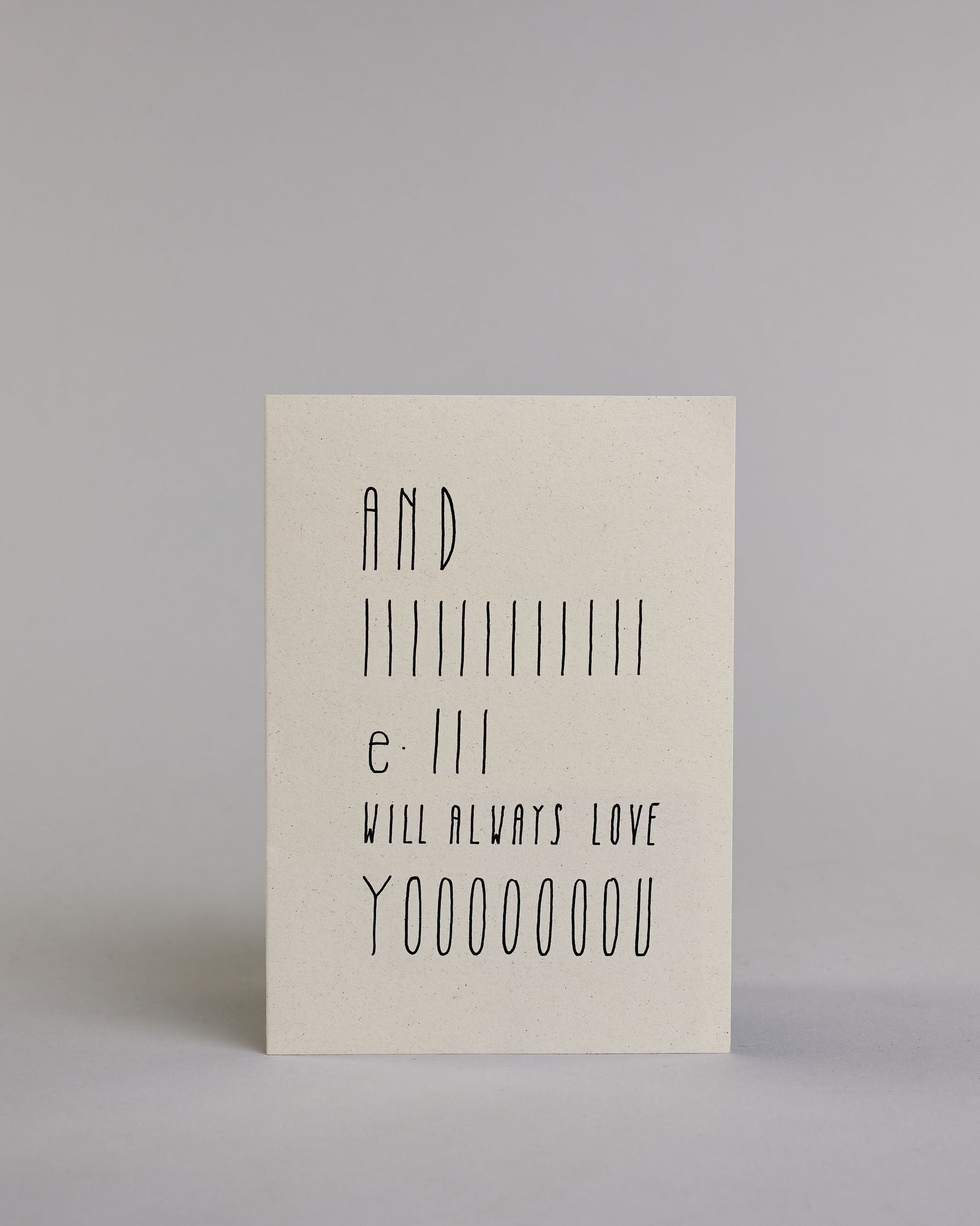 Klappkarte für Liebende auf Englisch mit schwarzer Kalligrafieaufschrift "And I will always love you" auf hellem Hintergrund. Der Text ist in folgende fünf Zeilen aufgeteilt: "AND", darunter "IIIIIIIIIIII", darunter "e-III", darunter "WILL ALWAYS LOVE", darunter "YOOOOOOOU" alle Zeilen sind in der gleichen dünnen geraden Kalligrafieschrift gestaltet und es ist eine Referenz zu dem Bekannten Whitney Houston Song, daher ist das "I" und das "you" in die Länge gezogen. Dazu ein rot-weißes handgeschöpftes Kuver…