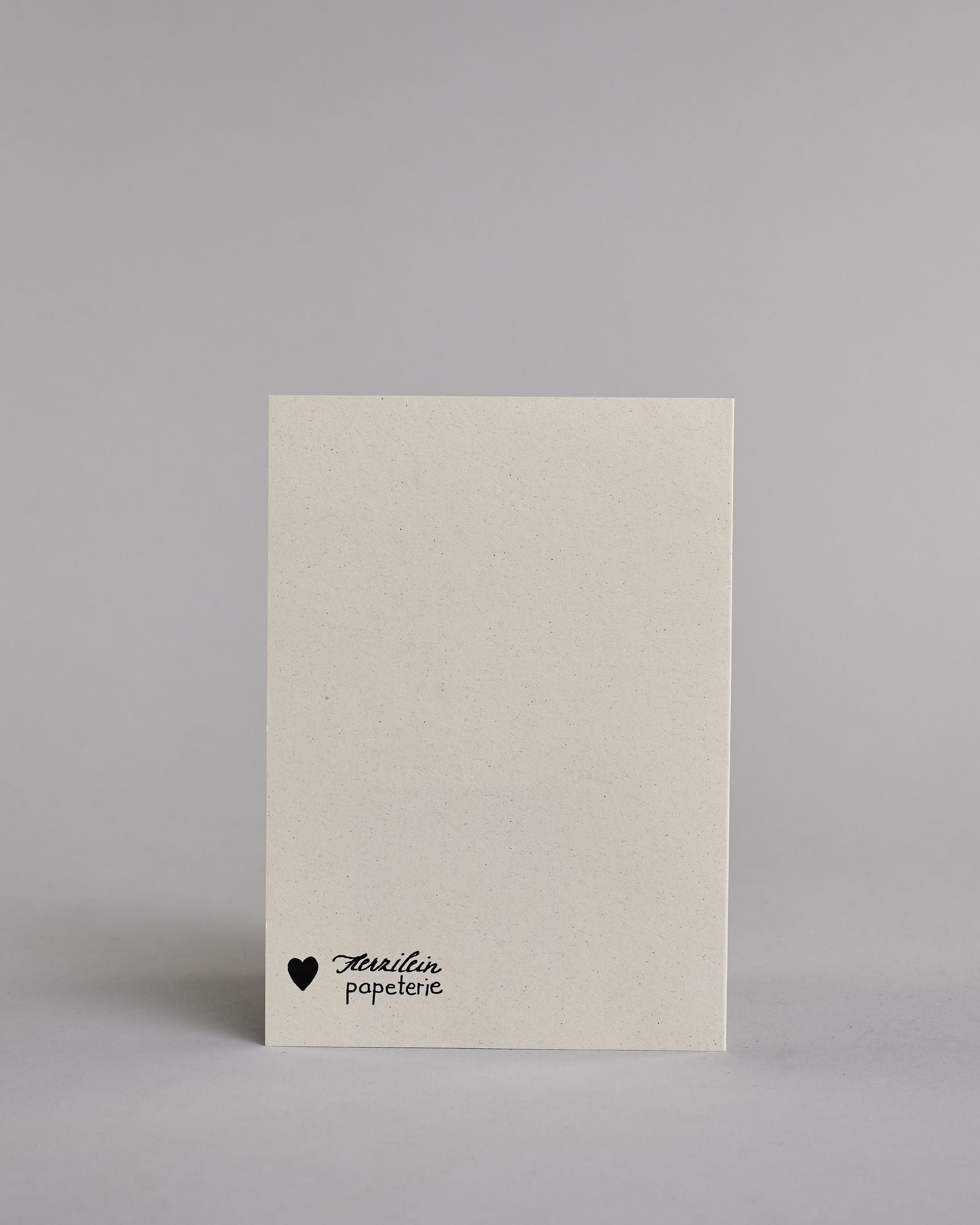 Klappkarte für Liebende auf Englisch mit schwarzer Kalligrafieaufschrift "And I will always love you" auf hellem Hintergrund. Der Text ist in folgende fünf Zeilen aufgeteilt: "AND", darunter "IIIIIIIIIIII", darunter "e-III", darunter "WILL ALWAYS LOVE", darunter "YOOOOOOOU" alle Zeilen sind in der gleichen dünnen geraden Kalligrafieschrift gestaltet und es ist eine Referenz zu dem Bekannten Whitney Houston Song, daher ist das "I" und das "you" in die Länge gezogen. Dazu ein rot-weißes handgeschöpftes Kuver…