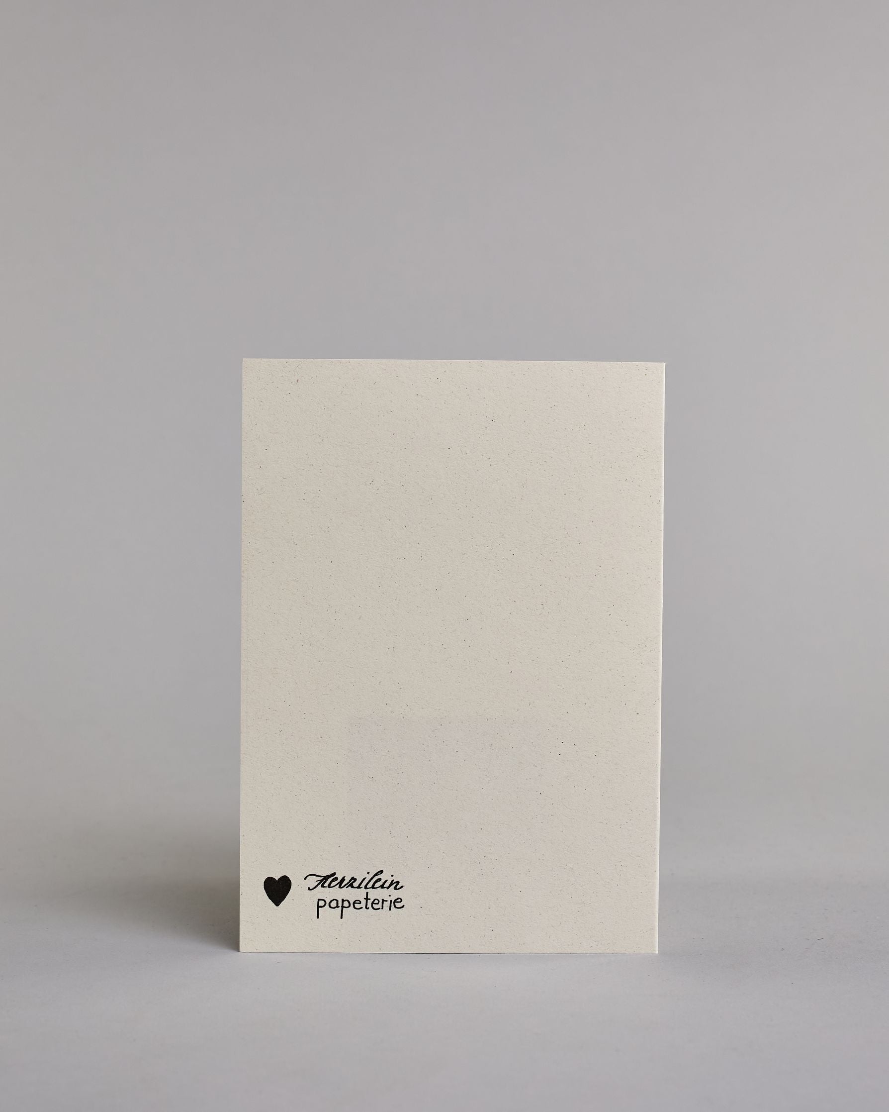 Klappkarte für Liebende in Englisch mit schwarzer Kalligrafieaufschrift "You make my heart smile" auf hellem Hintergrund. Der Text ist in folgende vier Zeilen aufgeteilt: "you", darunter "make", darunter "my heart", darunter "smile". Der Text ist in einer geschwungenen Schreibschrift mit punktueller Glitzerverzierung in der Mitte der Buchstaben gestaltet. Dazu ein grün-goldenes handgeschöpftes Kuvert. #4