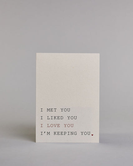 Klappkarte für Liebende auf Englisch mit schwarzer und roter Kalligrafieaufschrift "I met you I liked you I love you I'm keeping you." auf hellem Hintergrund. Der Text ist in folgende vier Zeilen aufgeteilt: "I MET YOU" in schwarzer, darunter "I LIKED YOU" in schwarzer, darunter "I LOVE YOU" in roter, darunter "I'M KEEPING YOU." in schwarzer Schrift, der Punkt hinter dem "YOU" ist ein kleines rotes Herz. Alle Zeile sind in einer Kalligrafieschrit gestaltet die an die tyische Schreibmaschinenschrift erinner…