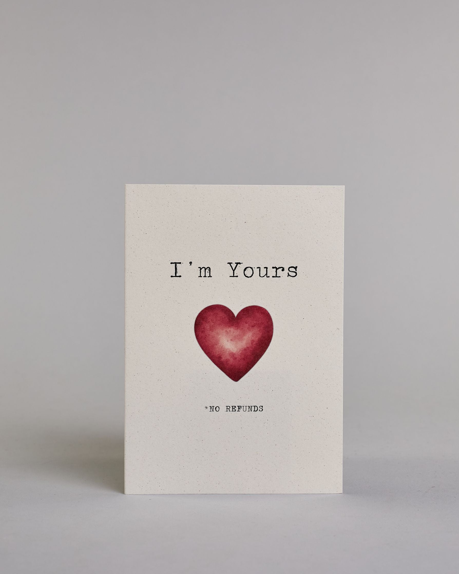 Klappkarte für Liebende auf Englisch mit schwarzer und Kalligrafieaufschrift "I'm yours *no refunds" mit einem Herz im Wasserfarbenstil auf hellem Hintergrund. Der Text ist in folgende zwei Zeilen aufgeteilt: "I'm Yours", darunter das rote Herz, darunter "*NO REFUNDS" beide Textzeilen in tyischer Schreibmaschinenschrift, das "*NO REFUNDS" ist allerdings viel kleiner, wie das Kleingedrukte in einem Vertrag. Dazu ein rot-weißes handgeschöpftes Kuvert. #1