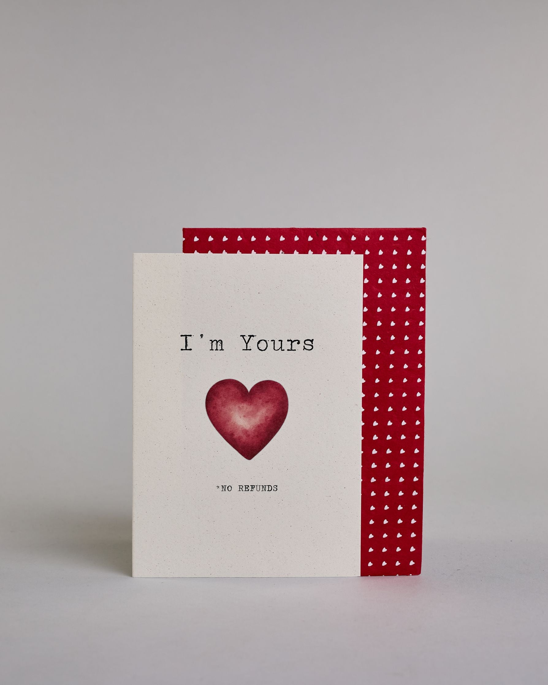 Klappkarte für Liebende auf Englisch mit schwarzer und Kalligrafieaufschrift "I'm yours *no refunds" mit einem Herz im Wasserfarbenstil auf hellem Hintergrund. Der Text ist in folgende zwei Zeilen aufgeteilt: "I'm Yours", darunter das rote Herz, darunter "*NO REFUNDS" beide Textzeilen in tyischer Schreibmaschinenschrift, das "*NO REFUNDS" ist allerdings viel kleiner, wie das Kleingedrukte in einem Vertrag. Dazu ein rot-weißes handgeschöpftes Kuvert. #2