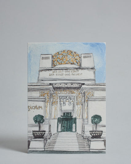 Die Vorderseite der Postkarte im Hochformat, gedruckt auf hochwertigem Papier. Diese zeigt die Wiener Secession vor blauem Himmel, gemalt von einer Wiener Künstlerin.