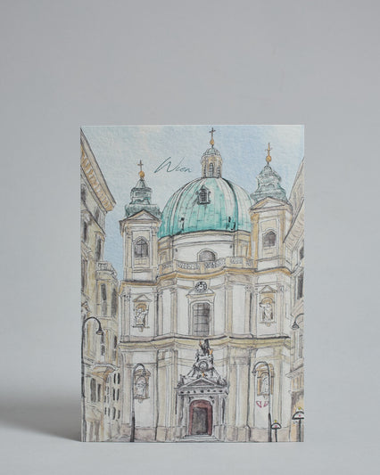 Die Vorderseite der Postkarte im Hochformat, gedruckt auf hochwertigem Papier. Diese zeigt die Wiener Peterskirche gemalt von einer Wiener Künstlerin. Über der Kuppel ist "Wien" in dezenter, geschwungener Schrift zu lesen.