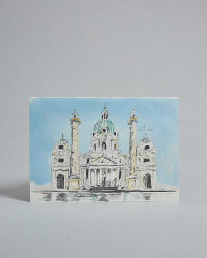 Die Vorderseite der Postkarte im Querformat, gedruckt auf hochwertigem Papier. Diese zeigt die Wiener Karlskirche vor blauem Himmel gemalt von einer Wiener Künstlerin. Im unteren Teil der Karte ist ein Brunnen zu sehen in dem sich die Kirche spiegelt.
Rechts neben der Kirche ist "Wien" in dezenter, geschwungener Schrift zu lesen.