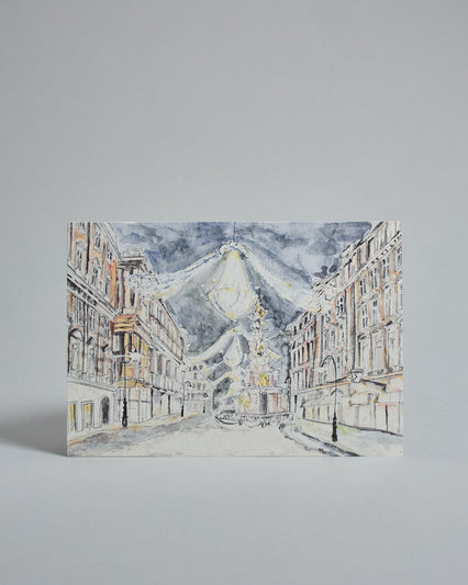 Die Vorderseite der Postkarte im Querformat, gedruckt auf hochwertigem Papier. Diese zeigt den Wiener Graben  mit Weihnachtsbeleuchtung gemalt von einer Wiener Künstlerin. Auch zu sehen ist die Pestsäule.