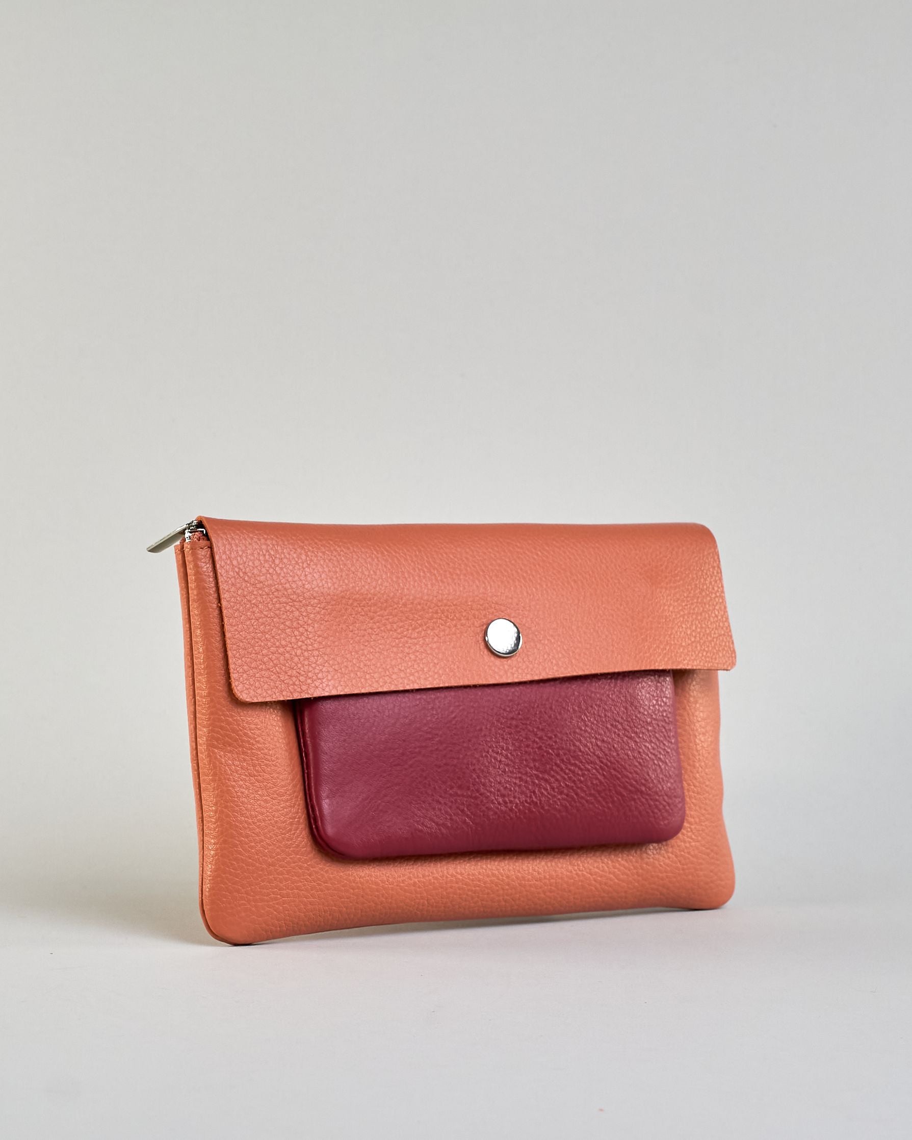 Kosmetiktasche aus Leder mit einem großen orangenen Zippfach und einem kleinen roten Zippfach vorne, darüber eine orangene Lasche mit Druckknopf. #2