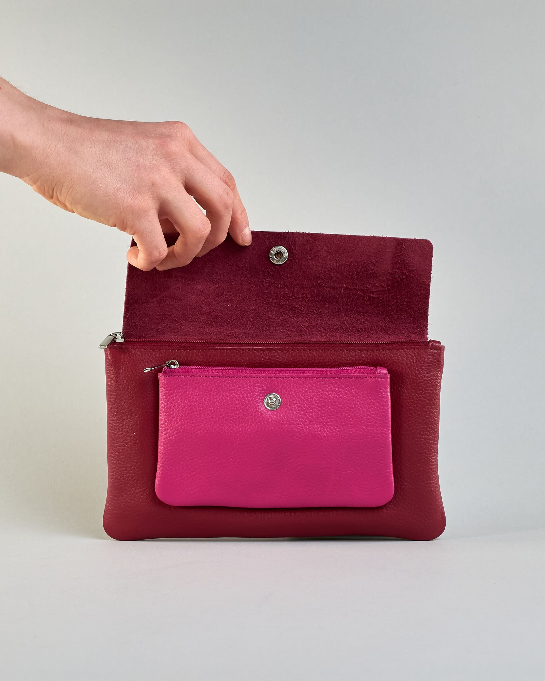 Kosmetiktasche aus Leder mit einem großen bordeauxroten Zippfach und einem kleinen pinken Zippfach vorne, darüber eine  bordauxrote Lasche mit Druckknopf. #4