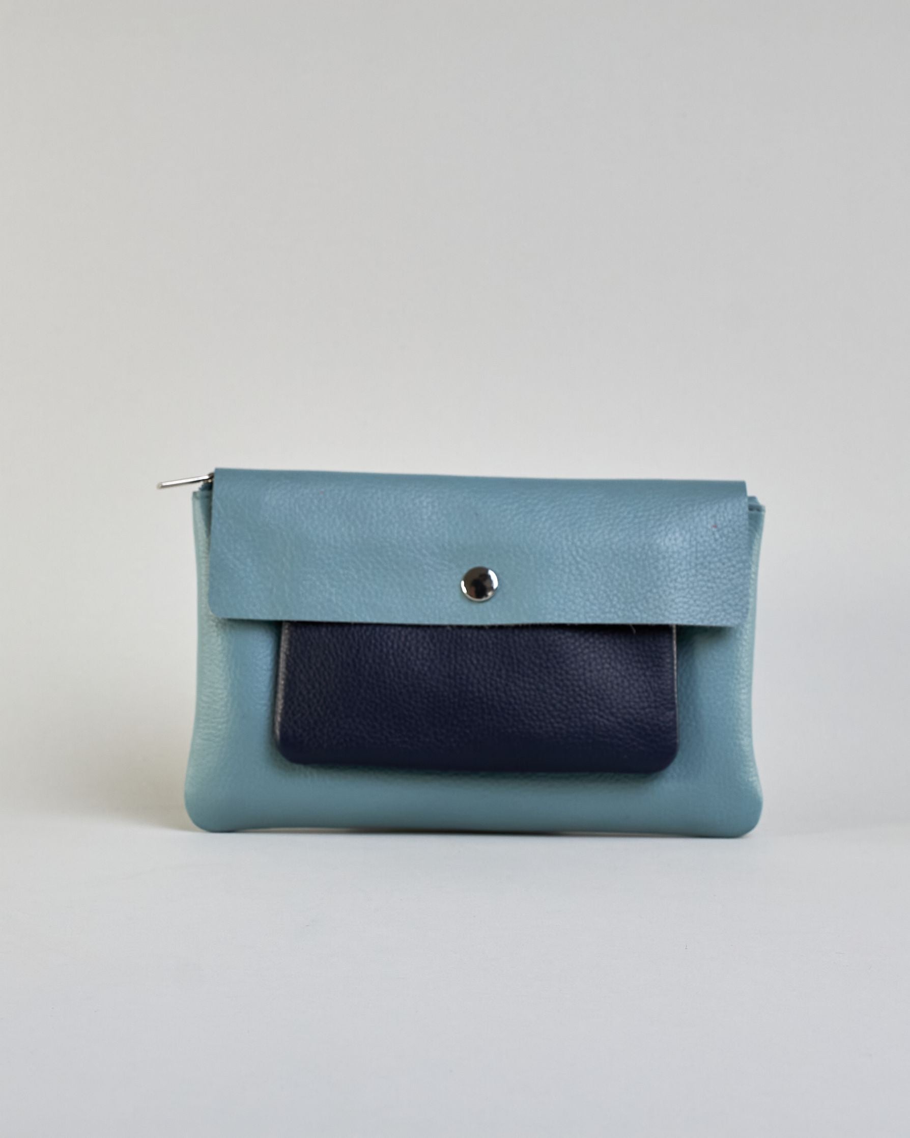 Kosmetiktasche aus Leder mit einem großen jeansblauen  Zippfach und einem kleinen dunkelblauen Zippfach vorne, darüber eine jeansblauen Lasche mit Druckknopf. #1