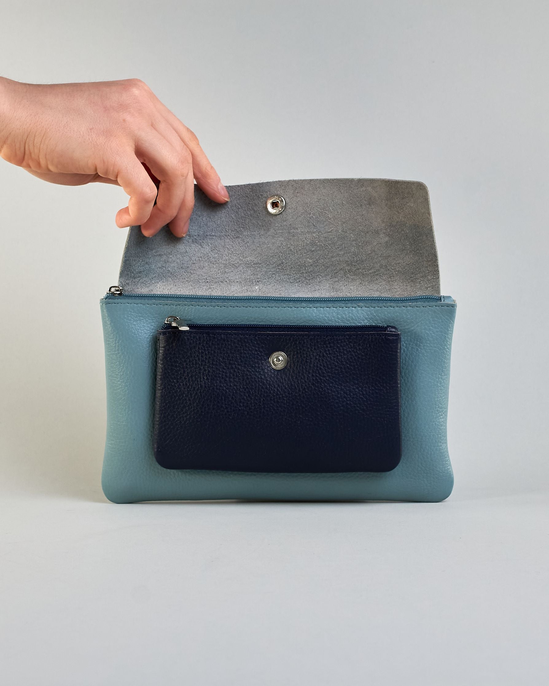 Kosmetiktasche aus Leder mit einem großen jeansblauen  Zippfach und einem kleinen dunkelblauen Zippfach vorne, darüber eine jeansblauen Lasche mit Druckknopf. #4