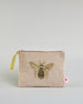 Beige Kosmetiktasche aus Baumwolle mit großer Biene aus Perlenstickerei mittig auf der Tasche. Goldene Quaste am Zippverschluss #1