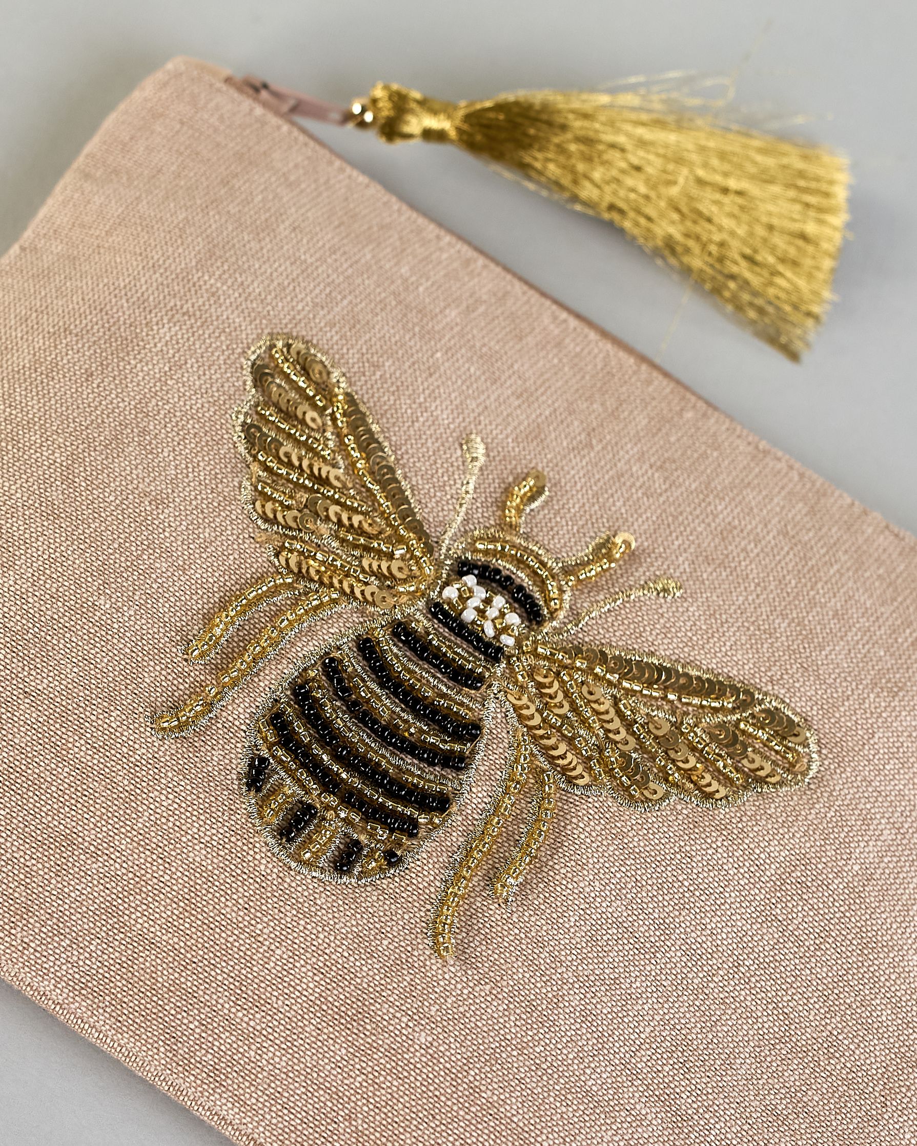 Beige Kosmetiktasche aus Baumwolle mit großer Biene aus Perlenstickerei mittig auf der Tasche. Goldene Quaste am Zippverschluss #3