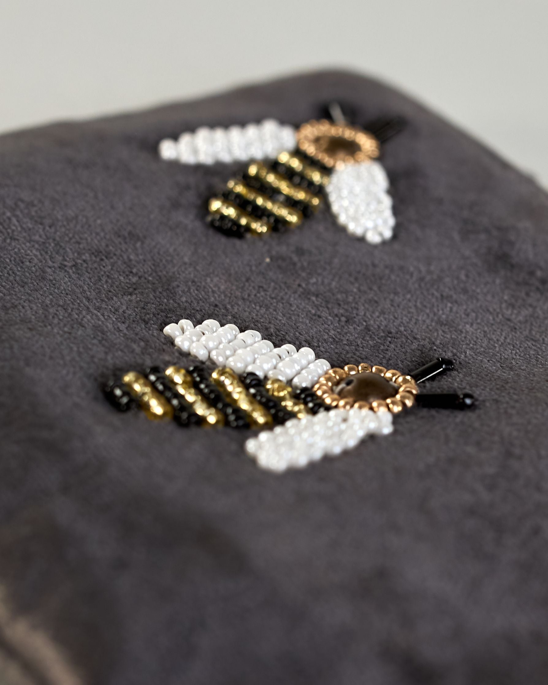 Graue kleine Kosmetiktasche aus Samt mit drei kleinen Bienen aus Perlenstickerei verteilt über die Tasche. Quaste am Zippverschluss #3