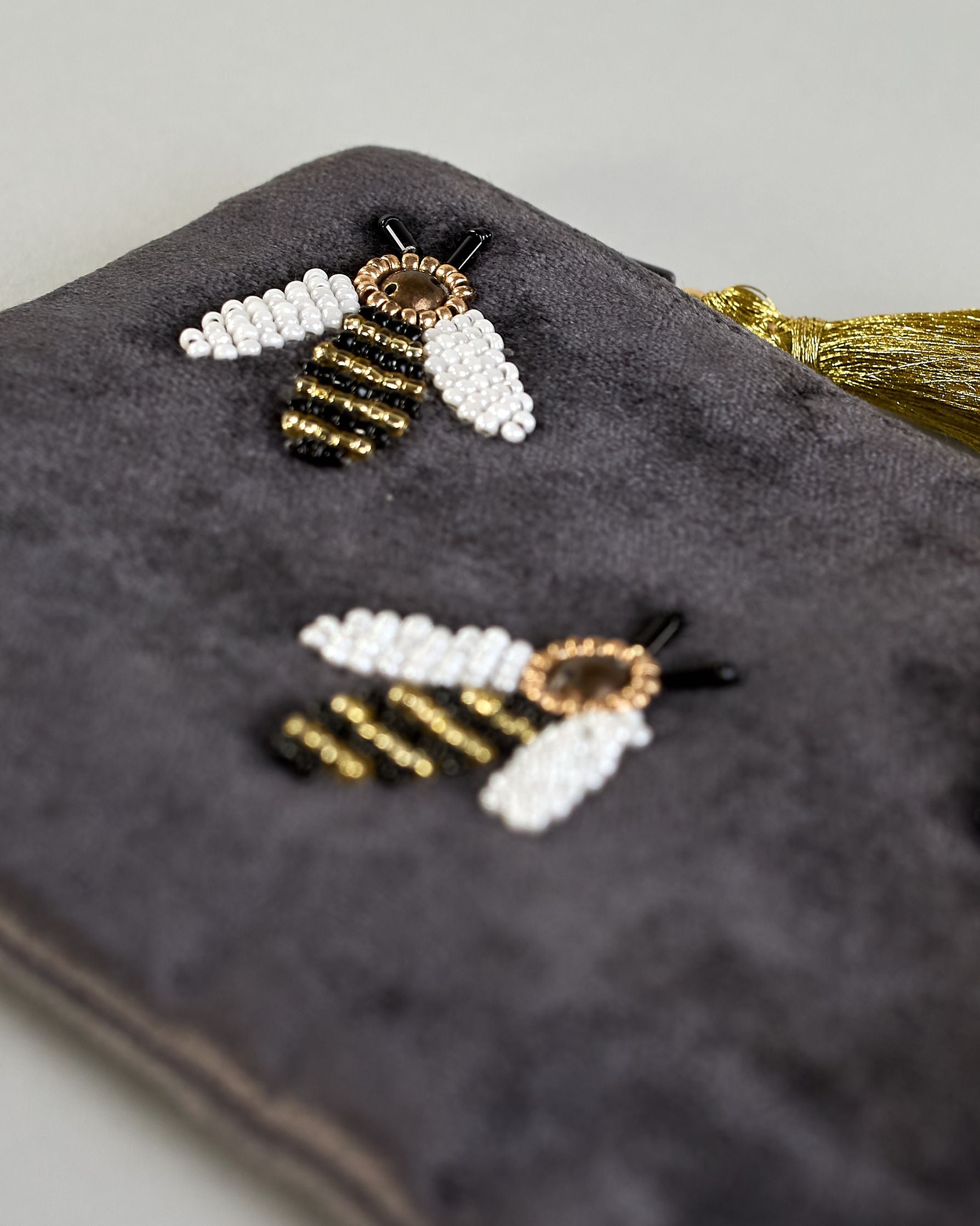 Graue kleine Kosmetiktasche aus Samt mit drei kleinen Bienen aus Perlenstickerei verteilt über die Tasche. Quaste am Zippverschluss #4