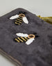 Graue kleine Kosmetiktasche aus Samt mit drei kleinen Bienen aus Perlenstickerei verteilt über die Tasche. Quaste am Zippverschluss #4