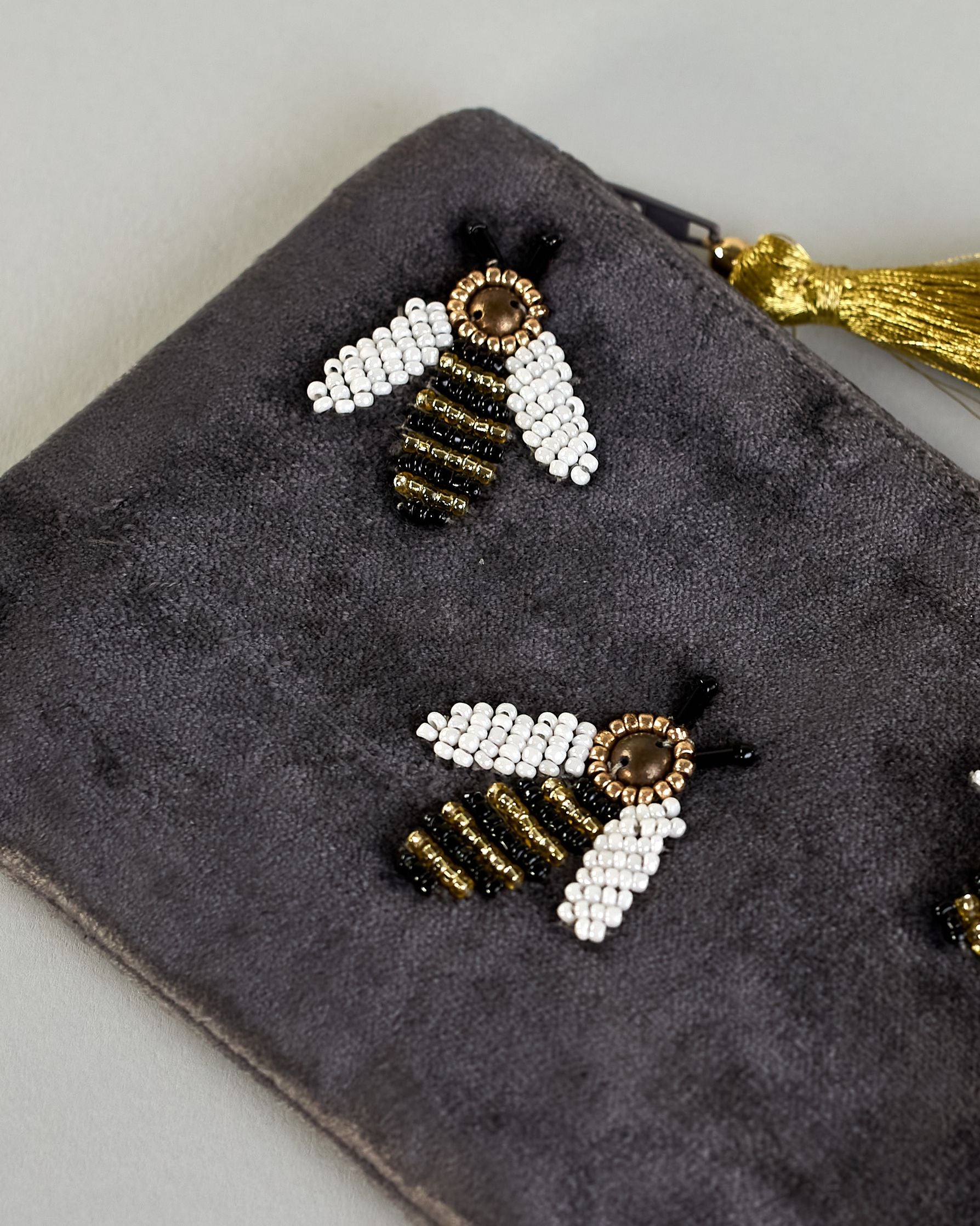 Graue kleine Kosmetiktasche aus Samt mit drei kleinen Bienen aus Perlenstickerei verteilt über die Tasche. Quaste am Zippverschluss #5