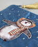 Blaue Kosmetiktasche aus Samt mit einem Pinguin mit Schal und Ohrenschützern der im Schnee tanzt. Mit schönen Details aus Perlen und Pailetten und einer goldenen Quaste am Zippverschluss #5