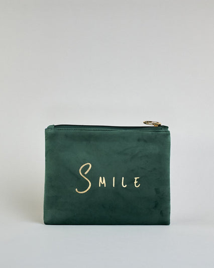 Dunkelgrüne  Kosmetiktasche aus Samtstoff mit großem goldenem Aufdruck "Smile" in der Mitte. Zipp mit goldenem Metallring zum Verschließen. Futter aus Satinstoff in Kontrastfarbe. #1