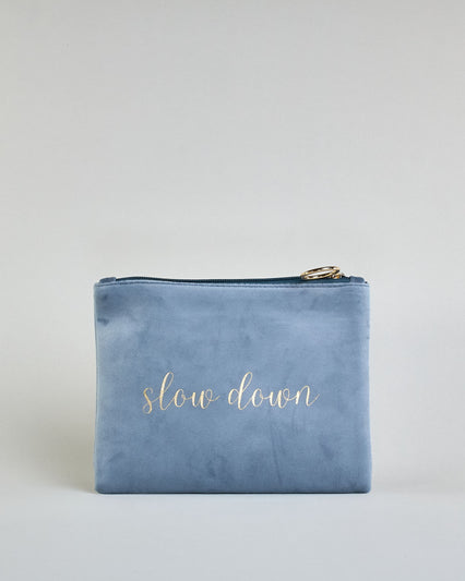 Hellblaue Kosmetiktasche aus Samtstoff mit großem goldenem Aufdruck "Slow down" in der Mitte. Zipp mit goldenem Metallring zum Verschließen. Futter aus Satinstoff in Kontrastfarbe. #1