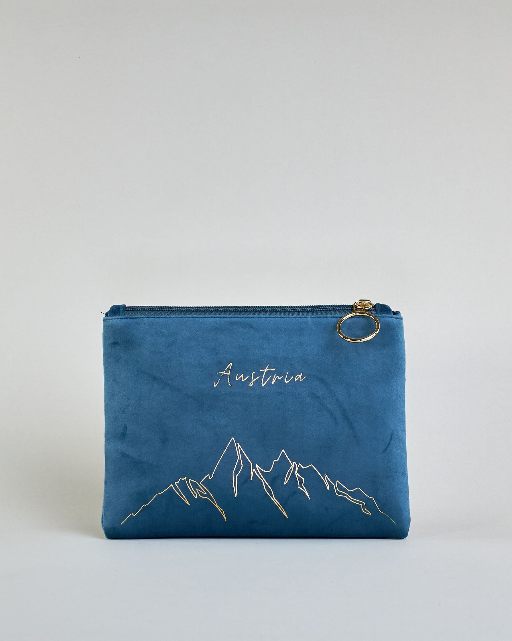 Blaue Kosmetiktasche aus Samtstoff mit großem goldenem Aufdruck "Austria" und Bergen in dünnen Linien in der Mitte. Zipp mit goldenem Metallring zum Verschließen. Futter aus Satinstoff in Kontrastfarbe. #1