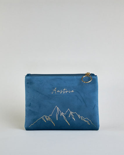 Blaue Kosmetiktasche aus Samtstoff mit großem goldenem Aufdruck "Austria" und Bergen in dünnen Linien in der Mitte. Zipp mit goldenem Metallring zum Verschließen. Futter aus Satinstoff in Kontrastfarbe. #1