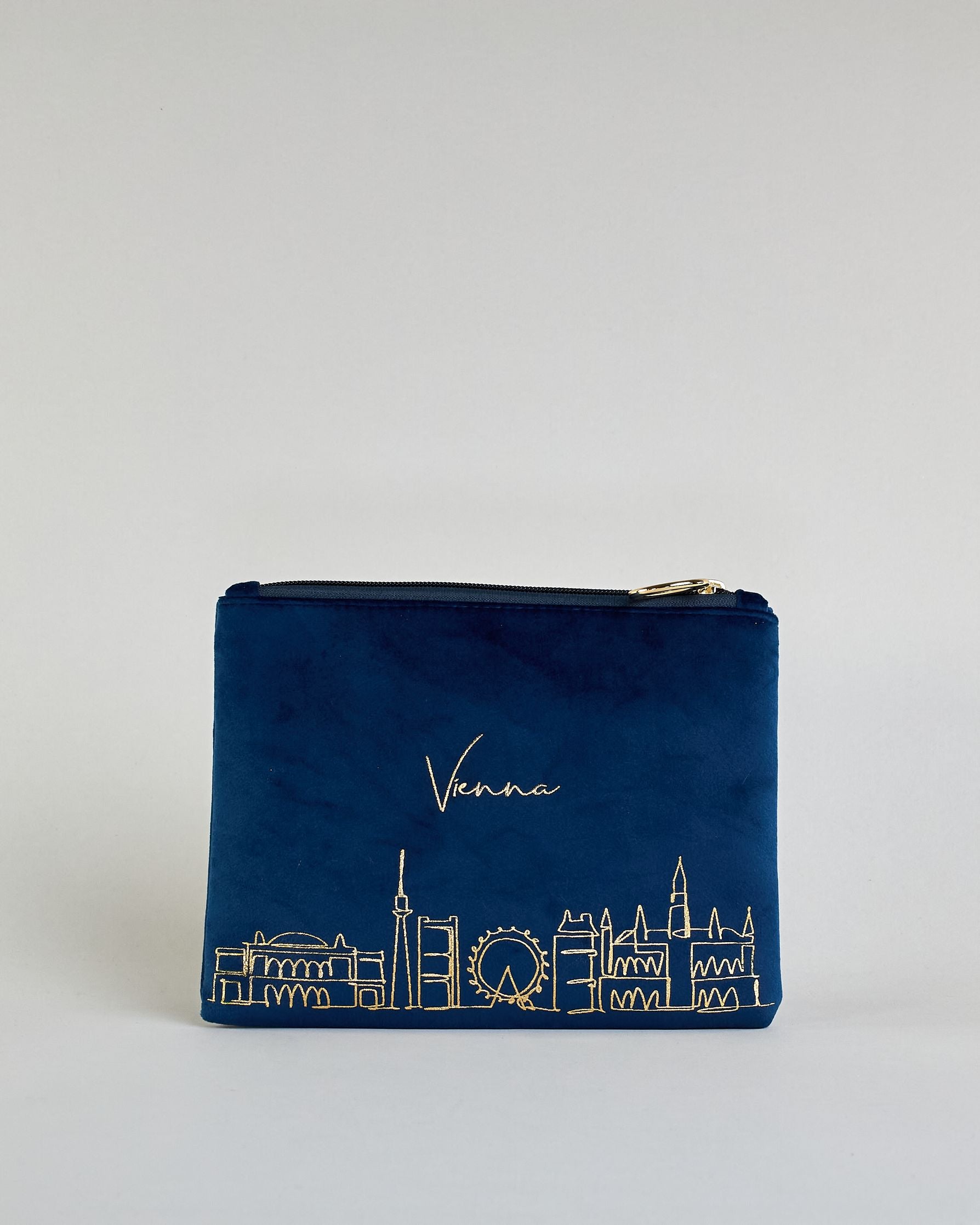 Dunkelblaue Kosmetiktasche aus Samtstoff mit großem goldenem Aufdruck "Vienna" und der Wien Skyline in dünnen Linien in der Mitte. Zipp mit goldenem Metallring zum Verschließen. Futter aus Satinstoff in Kontrastfarbe. #1