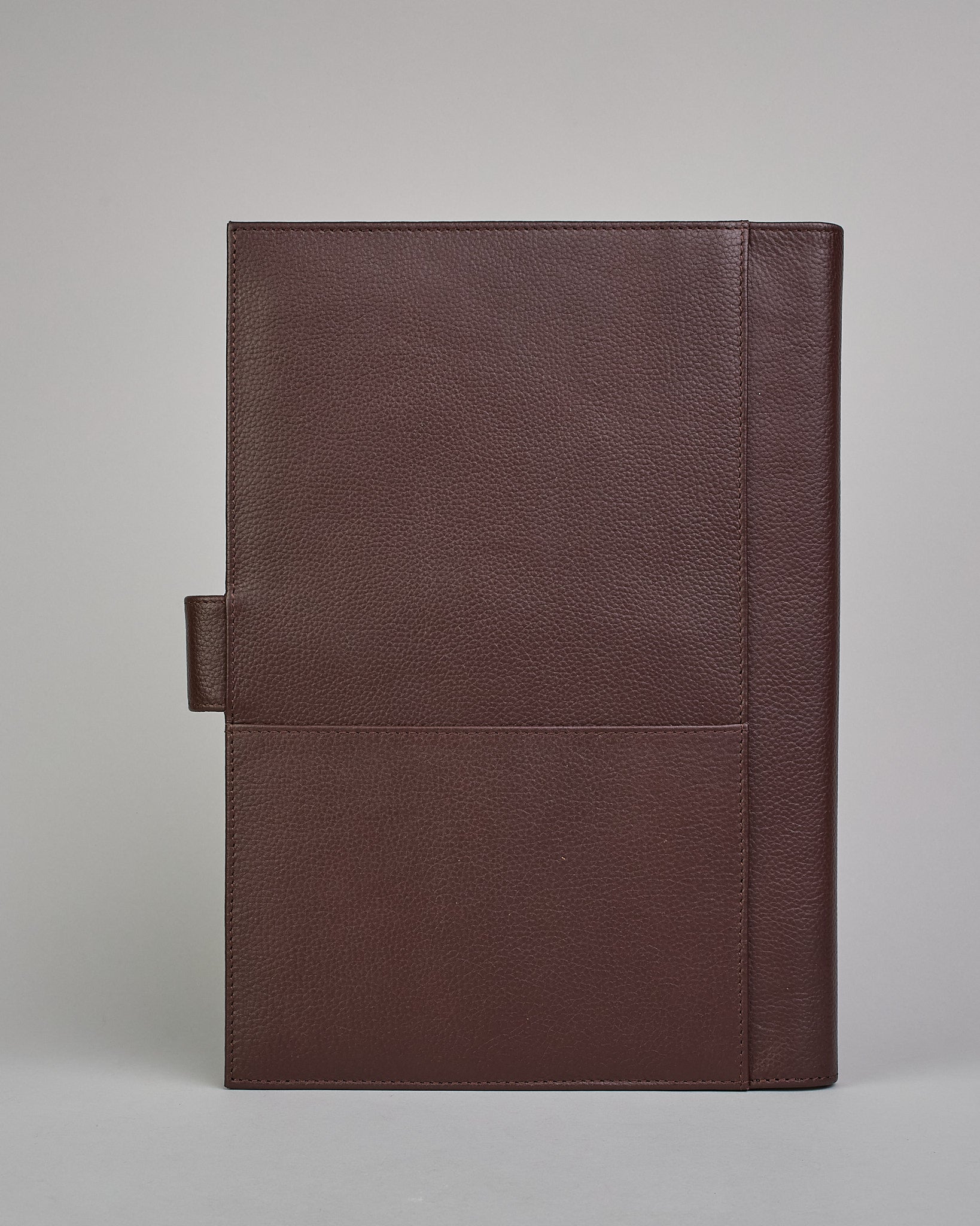 Dunkelbrauner Leder Notizbucheinband mit leichter Narbund. Der Einband hat außen ein flaches Fach in das ein Stift und das Handy gesteckt werden können. Das Notizbuch lässt sich seitlich mit einer Lasche und einem darunterliegenden Druckknopf verschließen. Innen bietet das Notizbuch rechts Platz um ein Buch einzustecken und links gibt es viele Fächer für weitere Notizzettel, Visitkarten und mehr. #3